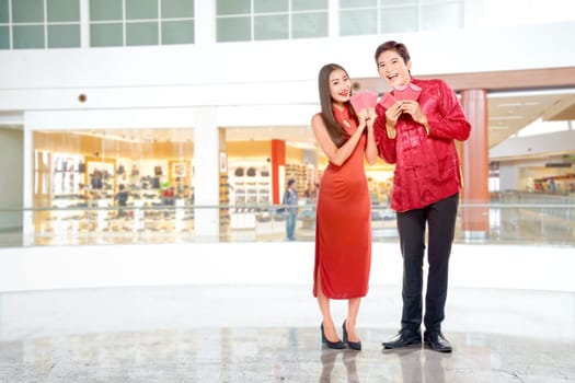 Asian Chinese couple in cheongsam dress holding red envelopes. Happy Chinese New Year