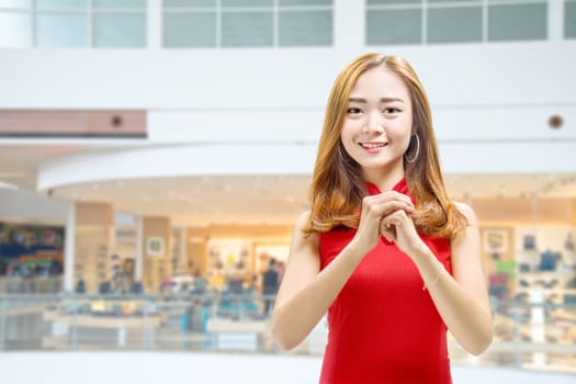 Asian Chinese woman in a cheongsam dress with congratulations gesture. Happy Chinese New Year