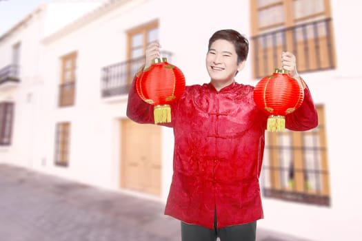 An Asian Chinese man in a cheongsam dress holding Chinese lantern. Happy Chinese New Year