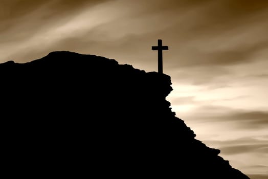 Christian cross on the edge of a cliff with a dark sky background