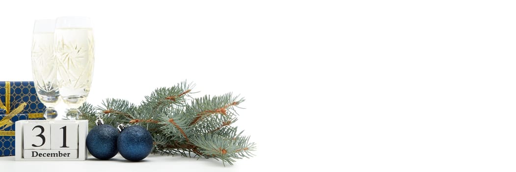 Still life with two champagne flutes, gift boxes and decoration with fir tree branch isolated on white background with copy space. New Year shopping. Greeting card