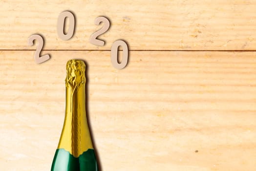 2020 on the wooden table with a champagne bottle for the new year party. Happy New Year 2020