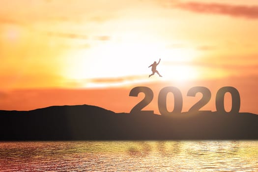 Silhouette of the fat man jumping above 2020 with a sunset sky background. Happy New Year 2020