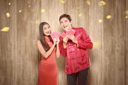 Asian Chinese couple in cheongsam dress holding red envelopes. Happy Chinese New Year