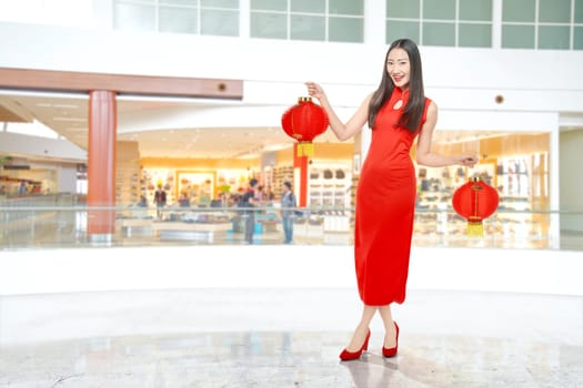 Asian Chinese woman in a cheongsam dress holding Chinese lantern. Happy Chinese New Year