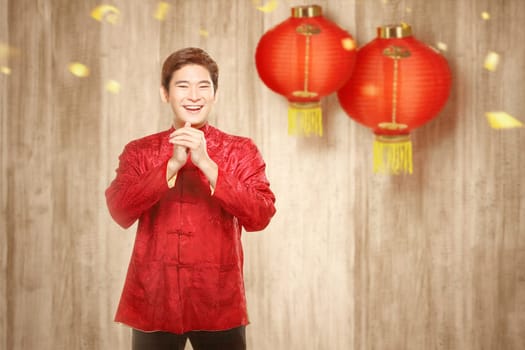 An Asian Chinese man in a cheongsam dress with congratulations gesture. Happy Chinese New Year