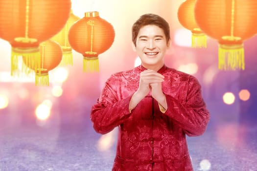 An Asian Chinese man in a cheongsam dress with congratulations gesture. Happy Chinese New Year