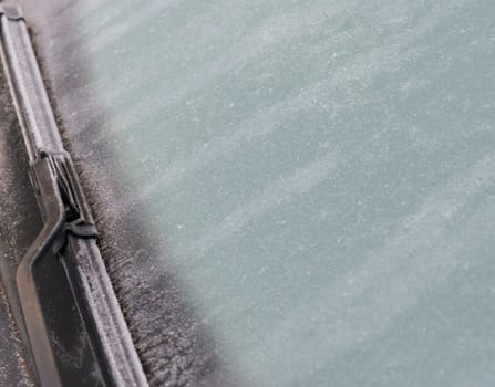 frozen windshield Close up photo and car wiper in winter. Frozen windshield of a car with ice and snow, concept of traffic. Risks in winter, copy space, selected focus