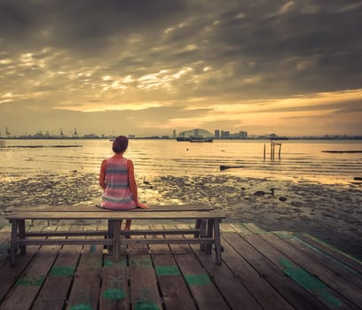 Tourist sitting at Yeoh jetty at sunrise, Georgetown, Penang, Malaysia