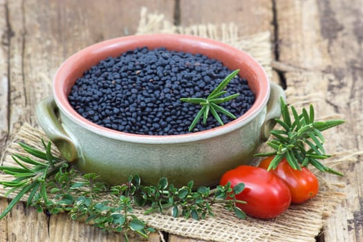 beluga lentils, tomatoes and herbs on wooden background