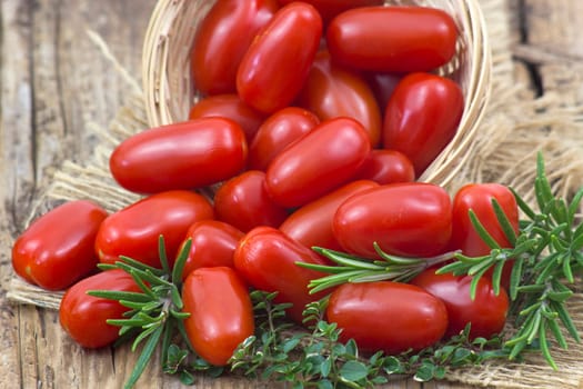 mini roma tomatoes and herbs on wooden background