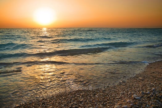Sunset above the sea. Big sun and waves at beach