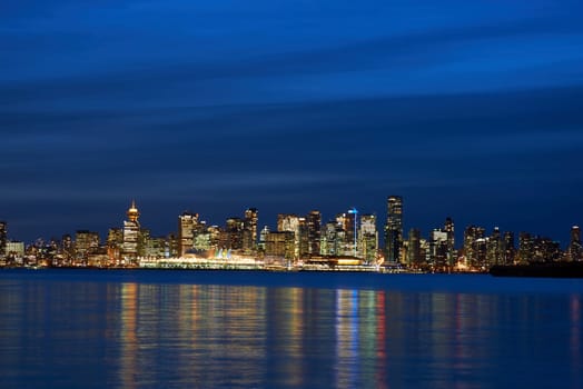 Night city, panoramic scene of downtown reflected in blue water. Vancouver, Canada