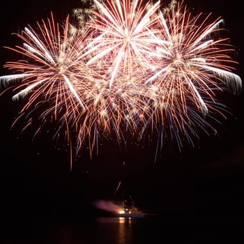 Red colorful holiday fireworks on the black sky background.