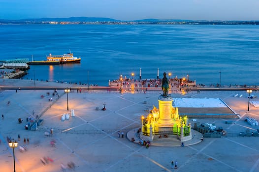 Aerial view to the illuminated Commerce square of Lisbon with statue of King Jose I, skyline with boat at Tagus river and city lights