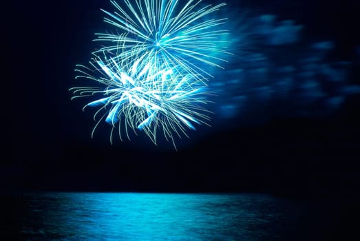 Blue colorful holiday fireworks on the black sky background.
