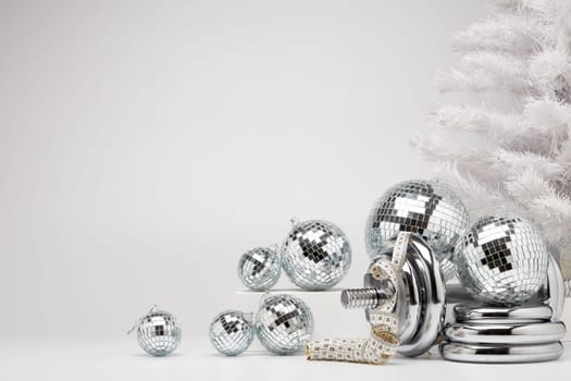 Dumbbells, Christmas fir tree and mirorr balls on white background with copy space. For design of advertising, web design. Christmas and New Year. Fitness, sport or healthy lifestyle concept.