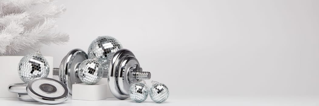 Dumbbells, Christmas fir tree and mirorr balls on white background with copy space. For design of advertising, web design. Christmas and New Year. Fitness, sport or healthy lifestyle concept.