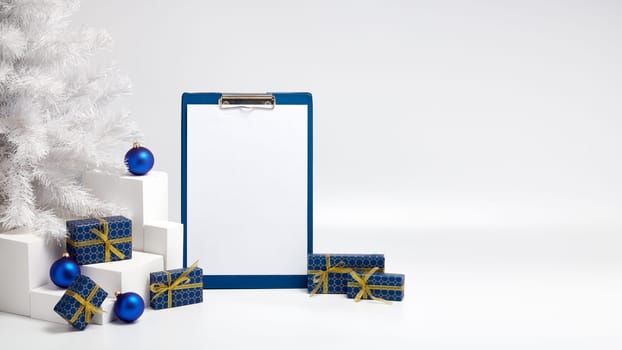 Gift boxes, blank clipboard, fir tree and Christmas decoration on white background with copy space. Christmas and New Year. For advertising. Greeting card. Winter sale