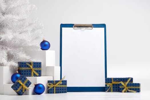 Gift boxes, blank clipboard, fir tree and Christmas decoration on white background with copy space. Christmas and New Year. For advertising. Greeting card. Winter sale