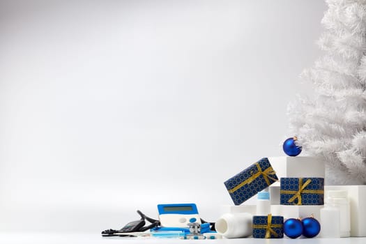 Stethoscope, medical devices, white fir tree, gift boxes and Christmas decorations on white background with copy space. Medical concept. Greeting card. New Year and Christmas.