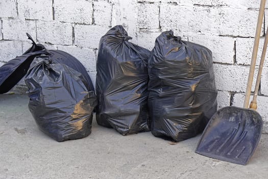 Three big blacks trash bags in front of wall