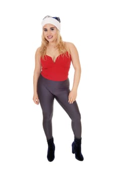 A beautiful young woman standing from the front in gray tights and.red top with a Santa hat, isolated for white background.