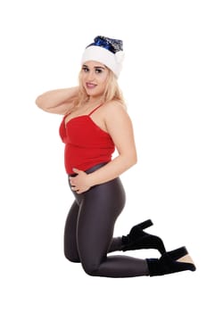 Beautiful young woman kneeling on the floor in a red top and gray .tights with a Santa hat, isolated for white background.