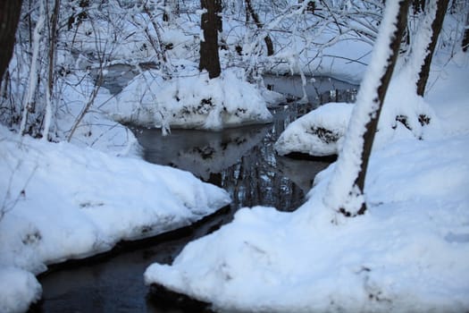 winter winding creek in a snowy forest close-up