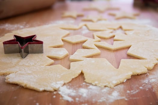 Cookie dough rolled out with star shapes cut out and star shaped cookie cutter