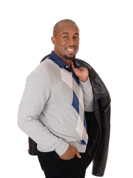 A handsome young African American man standing in jeans in profile, .with his jacket over his shoulder, isolated for white background.