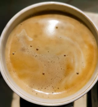 Cappuccino coffee in mug close up. Full cup of latte, mocha with milk froth . macro detail of hot caffeine drink. View from top