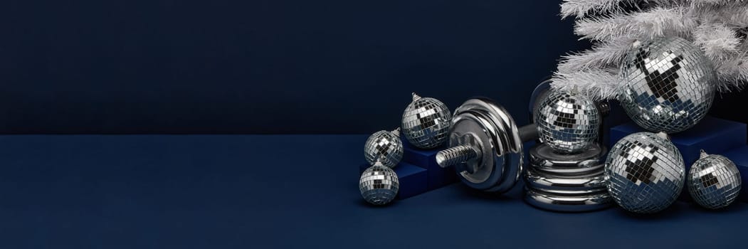 Dumbbells, Christmas fir tree and mirorr balls on dark blue background with copy space. For design of advertising, web design. Christmas and New Year. Fitness, sport or healthy lifestyle concept.