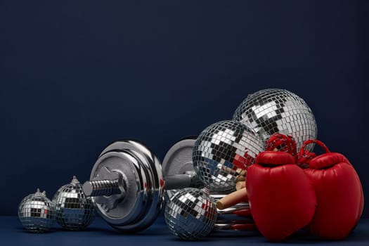 Dumbbell, boxing gloves, skipping rope, mirorr balls on dark blue background with copy space. For design of advertising, web design. Christmas and New Year. Fitness, sport or healthy lifestyle concept