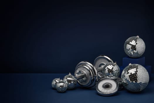 Dumbbell with weights and mirorr balls on dark blue background with copy space. For design of advertising, web design. Christmas and New Year. Fitness, sport or healthy lifestyle concept.