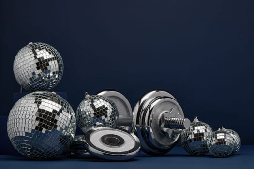 Dumbbell with weights and mirorr balls on dark blue background with copy space. For design of advertising, web design. Christmas and New Year. Fitness, sport or healthy lifestyle concept.
