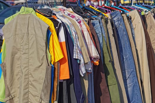 Shirts vests and pants hanging at clothes rails flea market