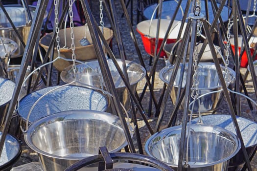 Many new metal cooking cauldrons with tripod legs