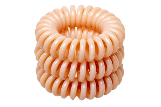 Hair care tools isolated. Close-up of cream colored elastic spiral scrunchies or hair bands for women hairstyling isolated on a white background. Tools from hairdresser and beauty salon. Macro.