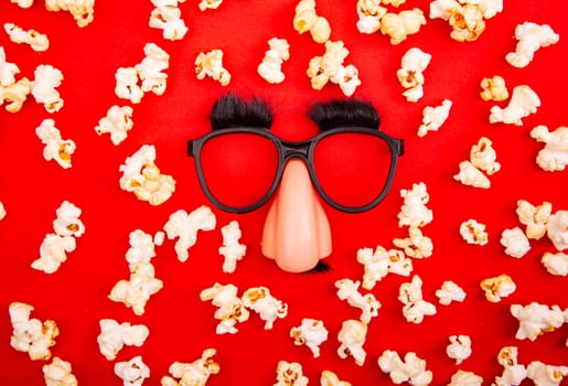 Popcorn and Funny Mask over red background