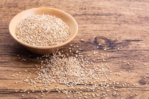 Unpeeled Sesame Seed in a wooden Bowl on brown background