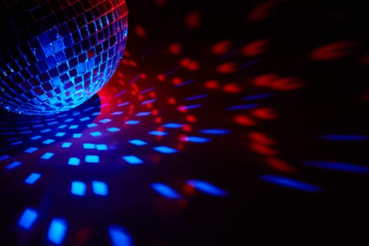 Glittering mirror disco ball on dark background with red blue lighting. Copy space. Weekend or holiday party. Nightclub. For advertising or web design. Entertainment, disco or music show background