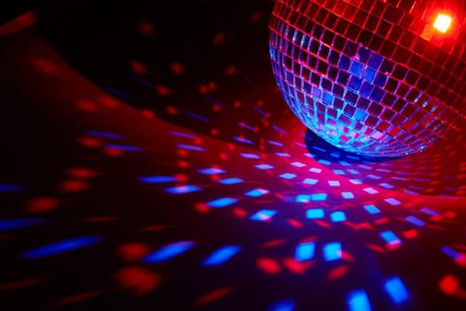 Glittering mirror disco ball on dark background with red blue lighting. Copy space. Weekend or holiday party. Nightclub. For advertising or web design. Entertainment, disco or music show background
