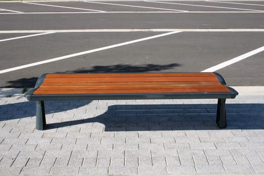 A resting bench made of wood on a parking lot