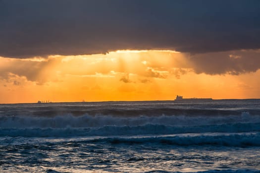 Ocean waves sunrise clouds ships silhouetted in morning color contrast on horizon