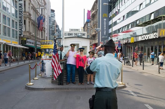 unknown tourists being photographed at checkpoint charlie Berlin. It's the best-known Berlin Wall crossing point between East and West Berlin during the Cold War.