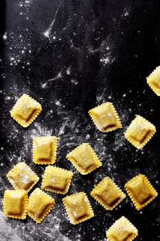 Fresh Italian Pasta Sheets Stuffed with Fillings. Formed in Square Shapes. Captured on Black Table.