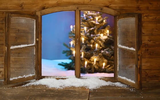 Attractive View of Lighted Christmas Tree on Snow from Vintage Wooden Window Pane During Holidays.