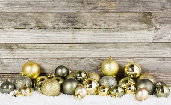 Close up Assorted Metallic Christmas Baubles For Decorations on the Snow with Wooden Wall Background.