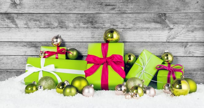 Close up Beautiful Apple Green Christmas Decorations with Assorted Size Presents and Balls on Snow. Display with Wooden Background.